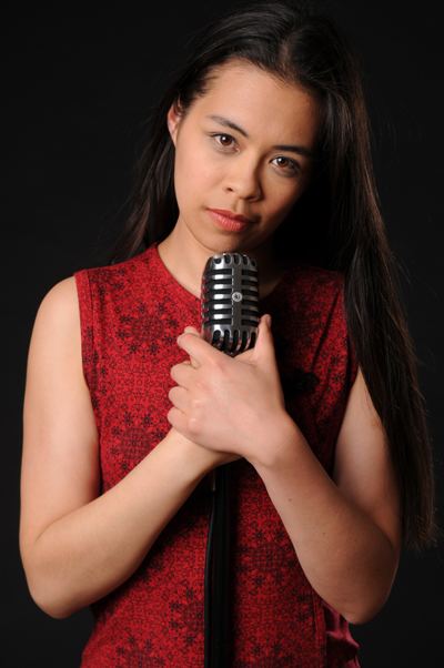 Ria Lina while holding a microphone wearing a red sleeveless shirt