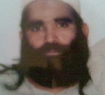 Riaz Basra with mustache and beard while wearing a white taqiyah and gray shirt