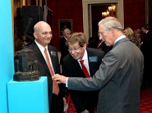 Richard Driehaus with a happy face while looking at something with two gentlemen wearing suits.