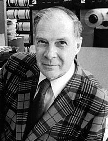 Richard Hamming smiling while wearing a checkered coat, long sleeves, and necktie