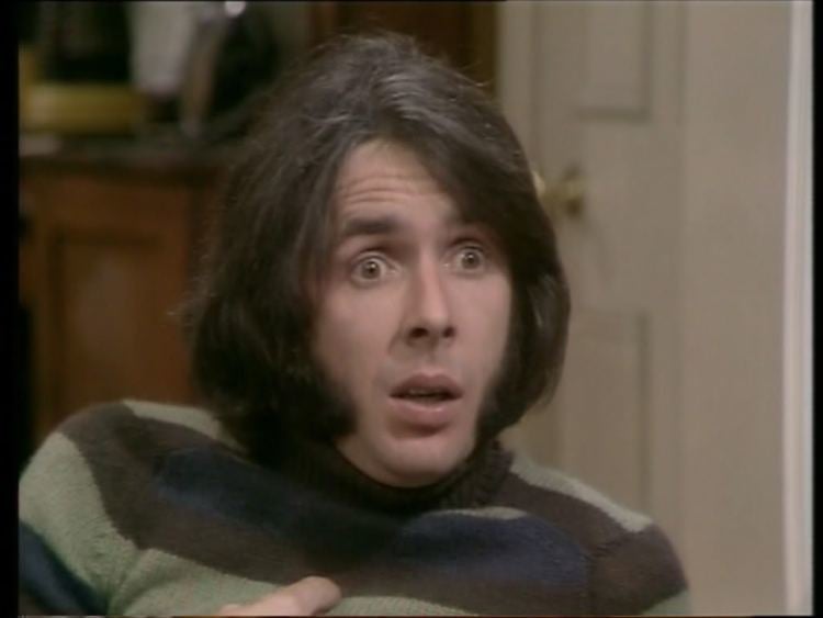 Richard O'Sullivan with a shocked face, and wearing a sweatshirt in a TV series scene from Robin’s Nest (1977-1981).