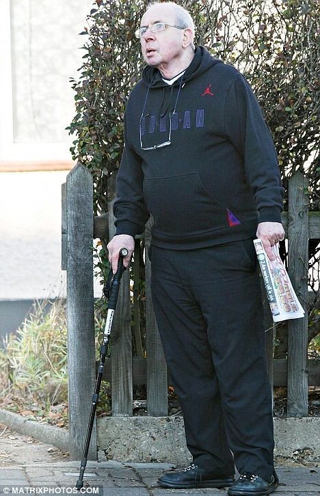 Richard O'Sullivan wearing eyeglasses, black hoodie, black pants and black shoes while holding a cane.