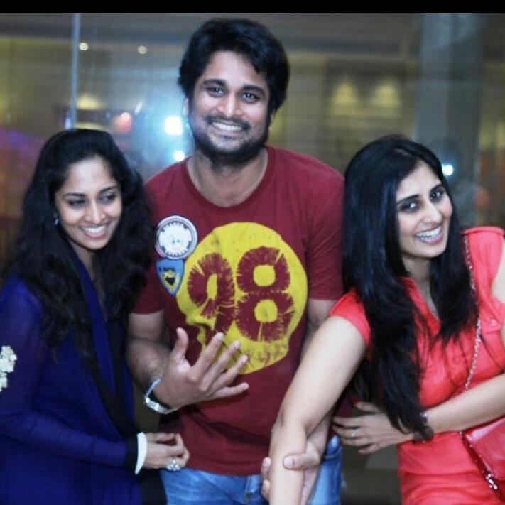 Richard Rishi with a smiling face, wearing a red shirt together with Shalini with smiling a smiling face and wearing a blue dress while Shamili also smiling and wearing an orange dress.