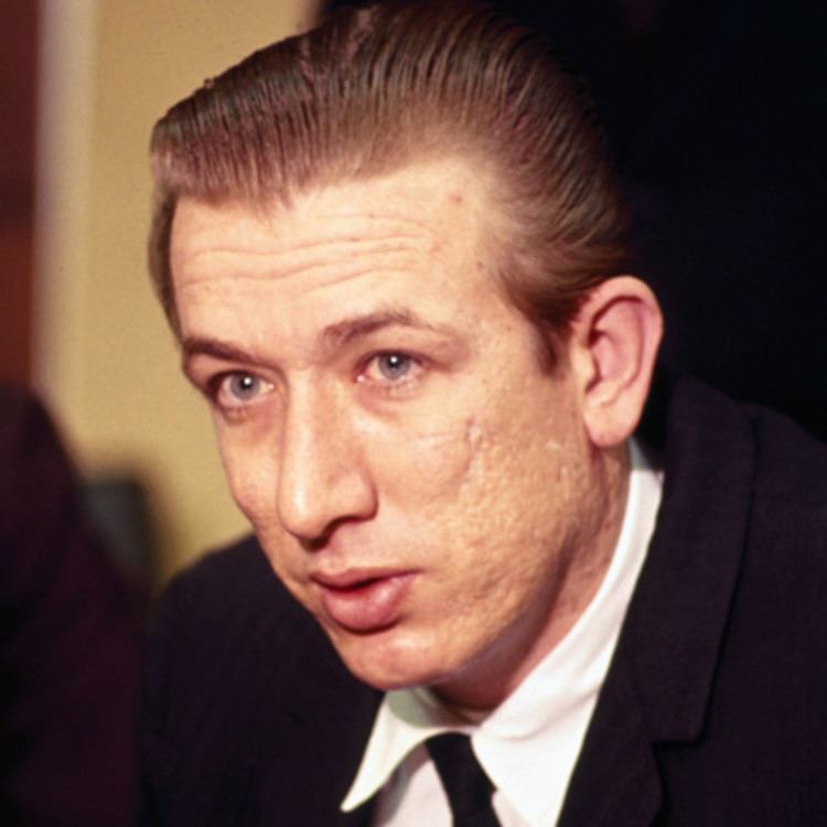 Richard Speck wearing a black coat, white long sleeves, and black necktie
