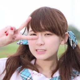 Rie Kaneko smiling while doing a V-sign finger pose with her hair in two ponytails and blue ribbons