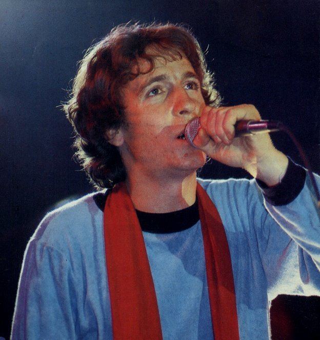 Rino Gaetano wearing a long sleeves shirt with red scarf while singing