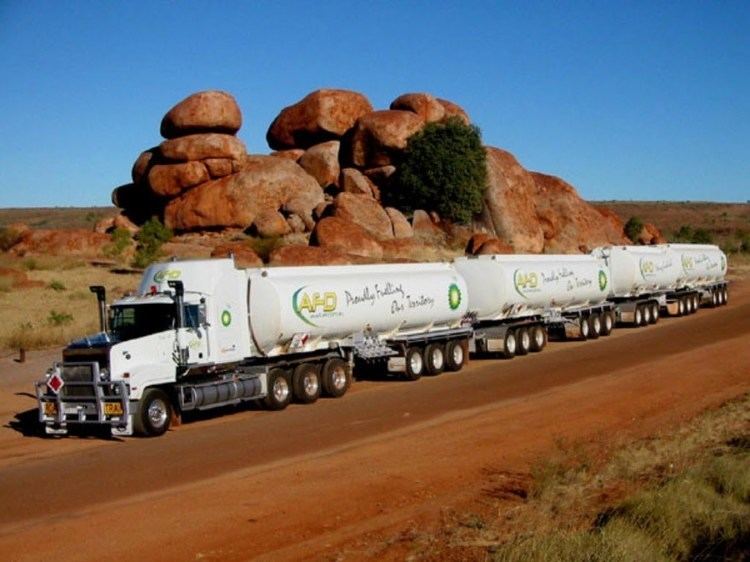 Road train crossing the road and a mountain rock on the side