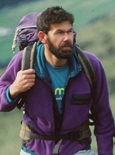 Rob Hall while walking wearing a purple jacket and a matching purple backpack