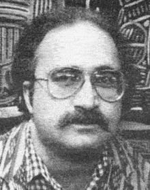 Robert Berdella with mustache while wearing eyeglasses and checkered long sleeves