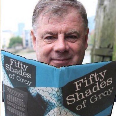 Robert Gray smiling closed mouth as he holds a Fifty Shades of Gray book.