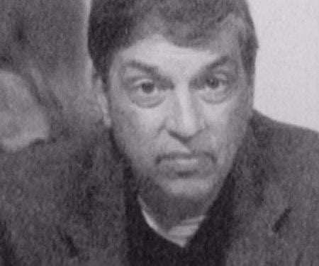 Robert Hanssen with a raised eyebrow while wearing a coat and shirt