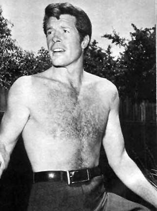 Robert Horton looking afar having a serious face with trees in the background, topless, wearing pants and a belt