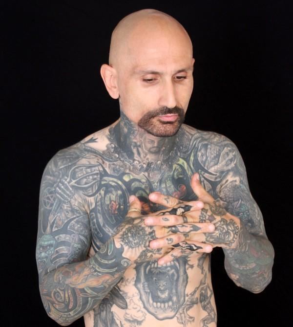 Robert LaSardo showing tattoos on his body, crossing his hands, with mustache and beard