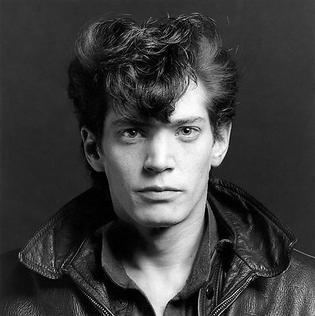 Robert Mapplethorpe, Self Portrait, 1980. Robert with a serious face and wearing a polo under a leather jacket