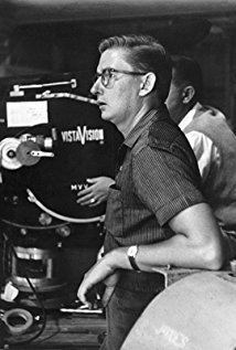 Robert Mulligan looking afar with a serious face on the set of the 1957 American biographical sports drama film, Fear Strikes Out, while wearing eyeglasses, wristwatch, and polo