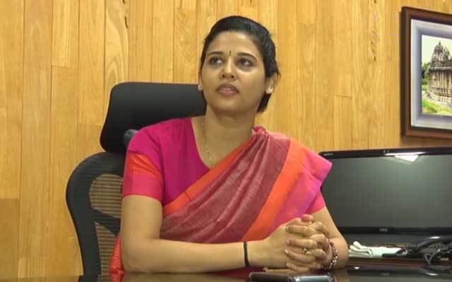 Rohini Sindhuri sitting on the chair at her office while wearing a pink and orange dress