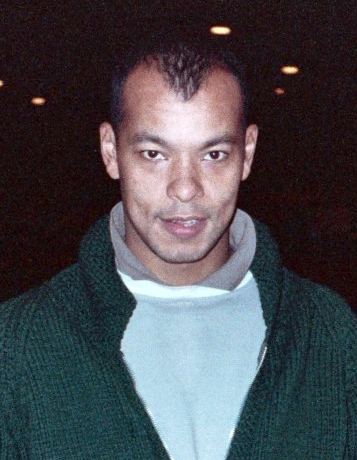 Roland Gift wearing a green jacket and blue and gray shirt