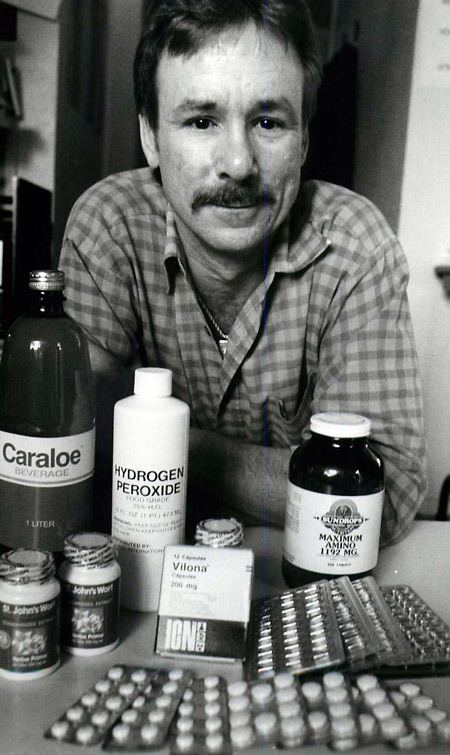 Ronald Dickson Woodroof with a mustache, wearing a checkered shirt and with different kinds of medicines.