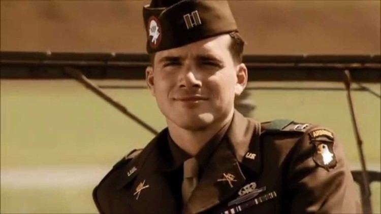 Matthew Settle as Ronald Speirs, with a tight-lipped smile while wearing an army service uniform in the 2001 TV Mini-Series, Band of Brothers