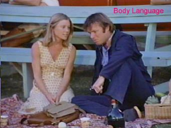 Ronne Troup in her yellow polka dot dress and James Coleman wearing dark blue coat, blue long sleeves and pants in the TV series Body Language