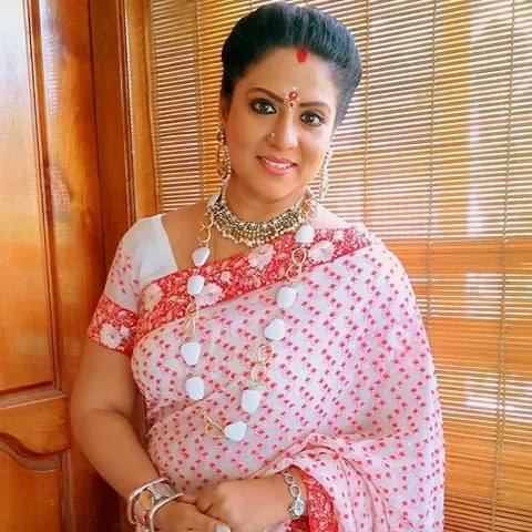 Roopa Sree wearing a red and white dress, necklaces, earrings, and bracelets