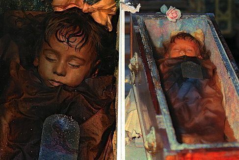 On the left, is the mummy of the little girl Rosalia Lombardo. On the right, is the mummy of the little girl Rosalia Lombardo (1918-1920) inside a coffin exhibited in the Capuchin Cemetery in Palermo.