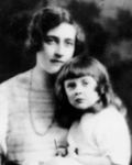 Rosalind Hicks sitting on the lap of her mother, Agatha Christie while she is wearing a dress and her mother wearing a striped dress and necklace