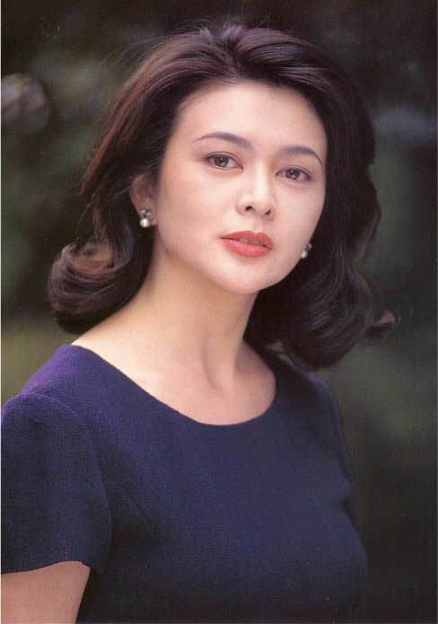 Rosamund Kwan wearing a dark blue blouse and earrings