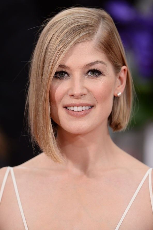 Rosamund Pike smiling during The Golden Globe Awards with short blonde hair while...