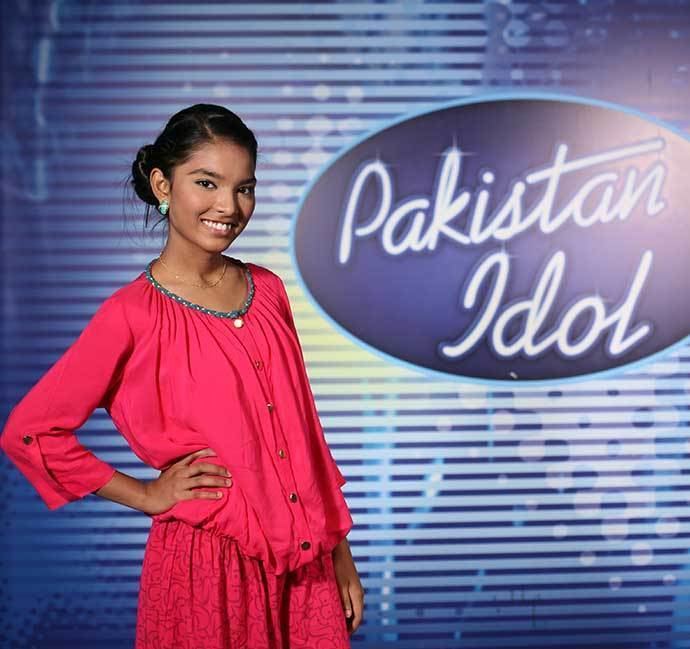 Rose Mary wearing earrings, a necklace, and a pink dress in Pakistan Idol.