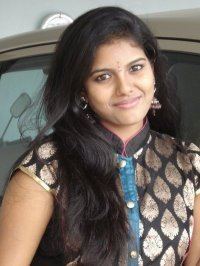 Roshini smiling and wearing a black floral dress.
