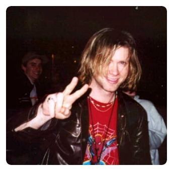 Ross Childress smiling while wearing a black leather jacket and spider man shirt