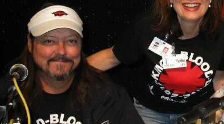 Phil Stone smiling and wearing beige cap and black printed shirt while the woman beside him smiling and wearing black printed shirt