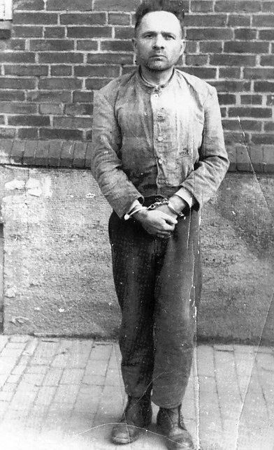 Rudolf Höss wearing long sleeves and pants while handcuffs around his wrists