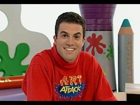 Rui Torres smiles while hosting on "Art Attack" wearing a red jacket