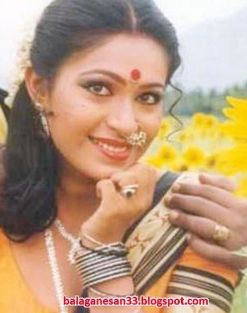 Rupini smiling while wearing a black and yellow dress and some pieces of jewelry