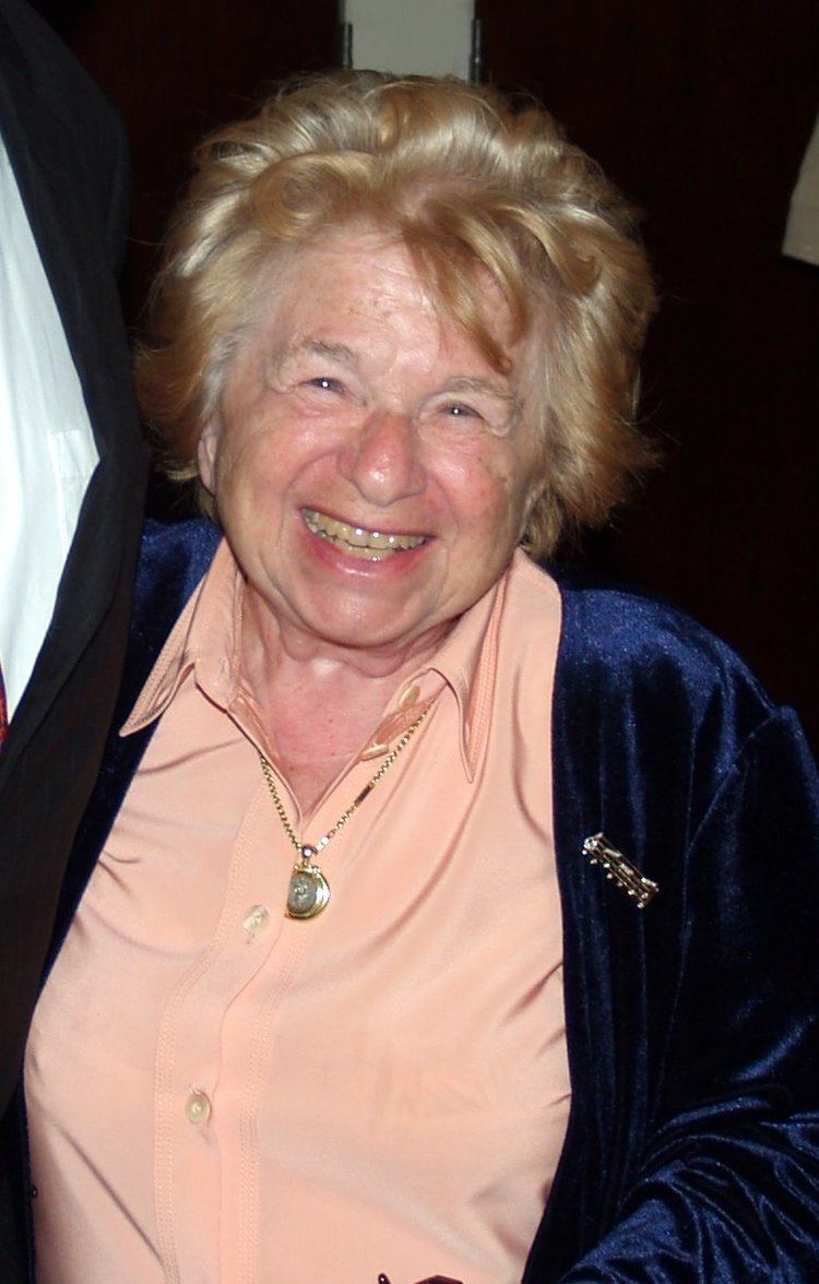 Ruth Westheimer's gorgeous smile while wearing blue velvet blazer, orange blouse and necklace