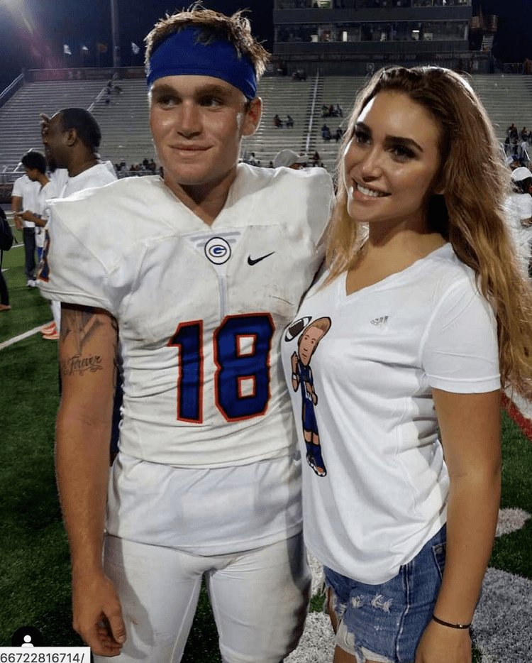 Rylee Martell smiling while wearing a white blouse and shorts together with her brother Tate Martell in a football jersey and blue turban