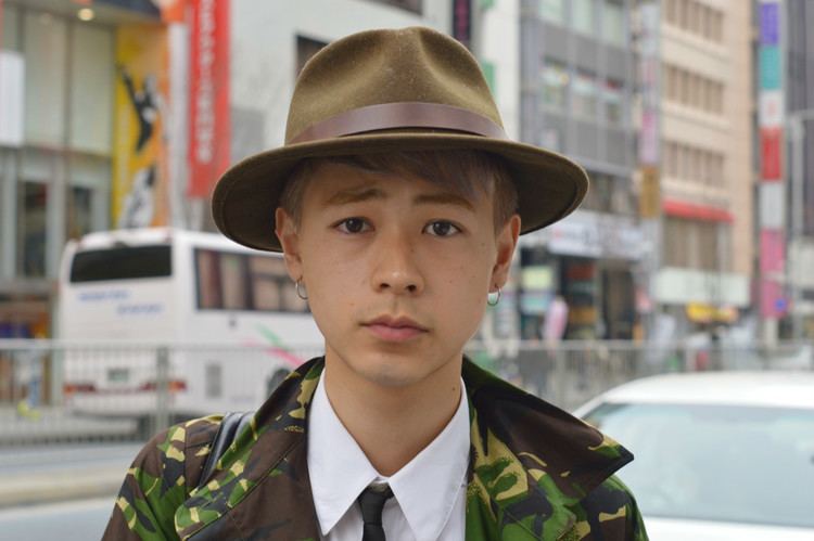 Ryo Narita wearing an army coat, white long sleeves, a black necktie and brown hat