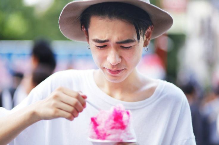 Ryo Narita eating ice cream while wearing a white t-shirt, gray hat, and earrings