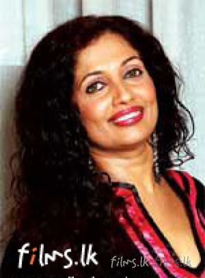 Sabeetha Perera smiling with black curly hair while wearing a black and pink blouse and earrings