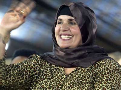 Safia Farkash smiling and waving at people while wearing a leopard designed dress and a dark burka.