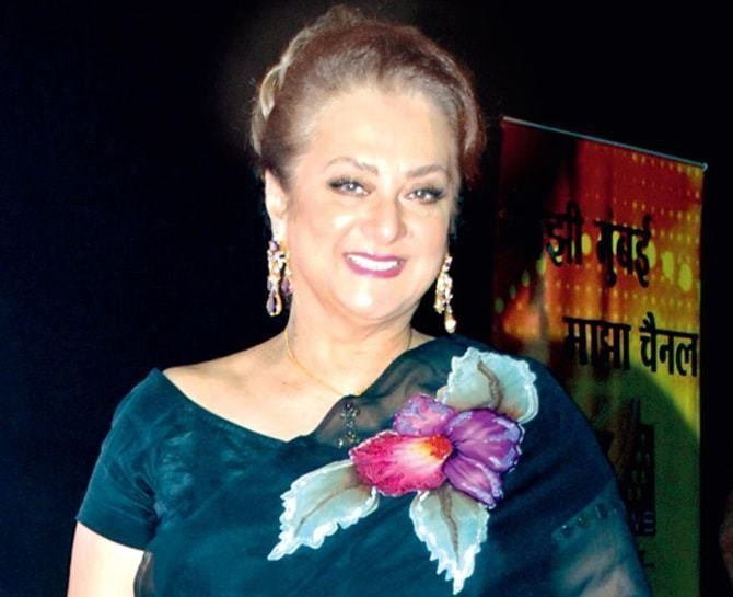 Saira Banu smiling while wearing blue floral dress and earrings