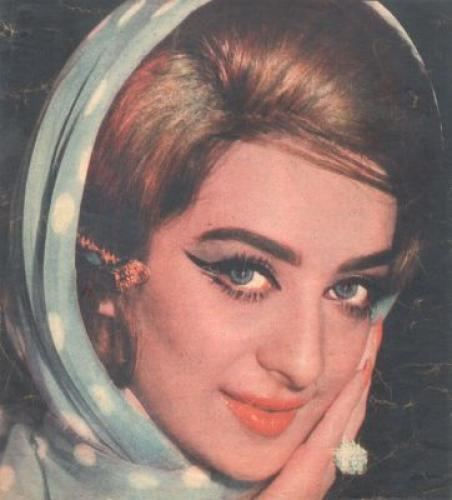 Saira Banu smiling and hand on her face while wearing blue polka dot headdress