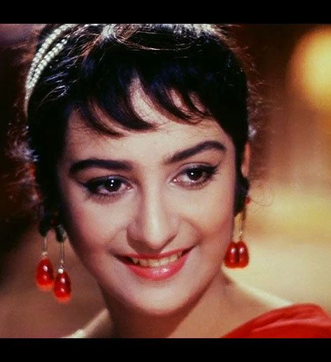 Saira Banu smiling while wearing red dress and red earrings