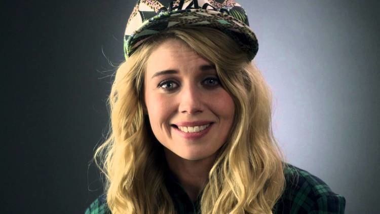 Salka Sól Eyfeld smiling while wearing a green checkered blouse and cap