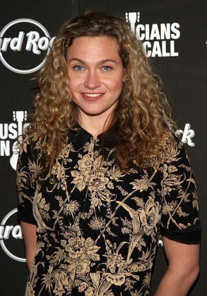 Sally Taylor with long curly hair and wearing a floral dress.