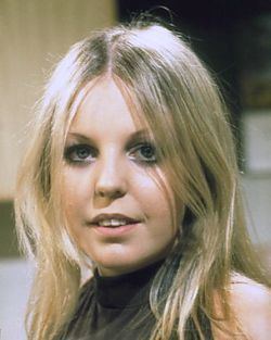 Sally Thomsett smiling, with wavy blonde hair, and wearing a dark green halter top.