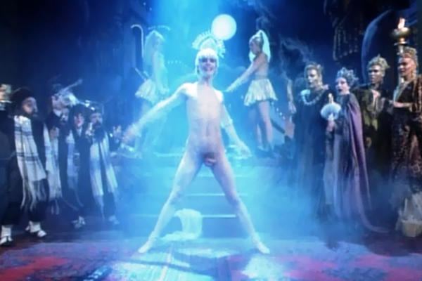 A naked man smiling while dancing at the center in a scene from the 1988 film, Salome's Last Dance