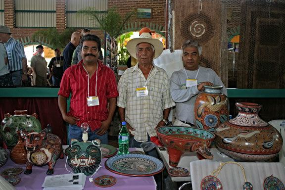 Salvador Vázquez, a famous Mexican potter, posing with his ceramics and companions while wearing a white sombrero along with a checkered, long-sleeved polo.